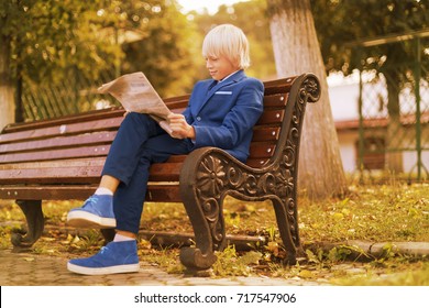 Autumn, Boy In The Park Reading A Newspaper