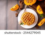 Autumn breakfast dessert, pumpkin waffle. Stack of homemade belgian pumpkin waffles with honey and spices, copy space