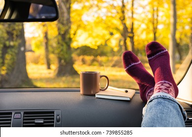 Autumn Car Trip. Woman Feet In Warm Wool Socks And Cup Of Tea In The Car