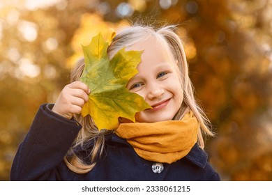 Autumn Child Girl Playing with Maple Leaf. Hello Autumn. Stylish Children Kid Having Fun In Autumn Park. Kids Autumn Sale. - Powered by Shutterstock