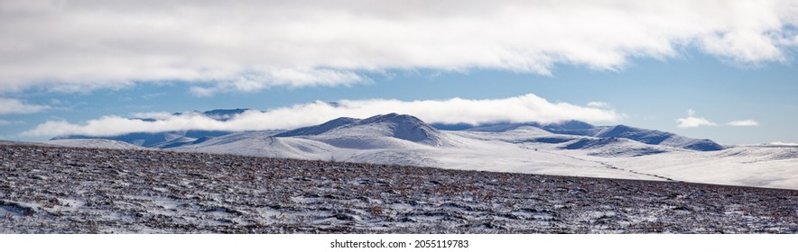 Autumn Chukotka Landscape-panorama With Snow, Tundra And Hills With Clouds Lying On Them.