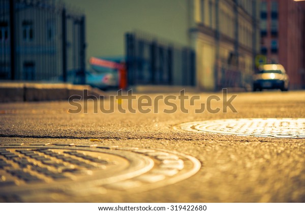 Autumn in the city, the street with parked car.\
View from the hatches on the pavement level, image in the\
yellow-blue toning