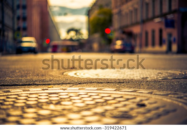 Autumn in the city, the street with parked cars.\
View from the hatches on the pavement level, image in the\
yellow-blue toning