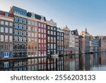 As autumn cloaks Amsterdam in shades of gold and orange, the charm of the city iconic canal houses glistens in the serene waters. Damrak Amsterdam at sunrise