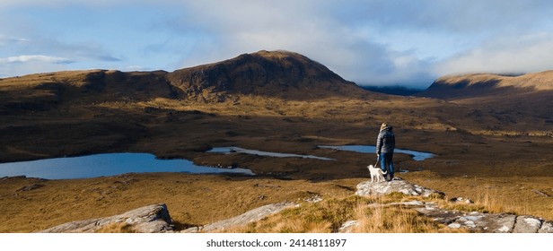 Autumn colours of Scottish moorland with woman and dog looking at the view, mountains in the background - Powered by Shutterstock