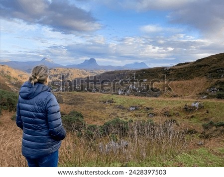 Autumn colours of Scottish moorland with woman  looking at the view, mountains in the background