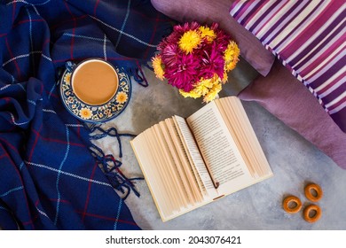 Autumn composition. Coffee chrysanthemums book plaid top view flat layout. The concept of comfort, autumn-winter cold. Mockup of winter design. Cozy still life with a blue blanket, pillows, bagels