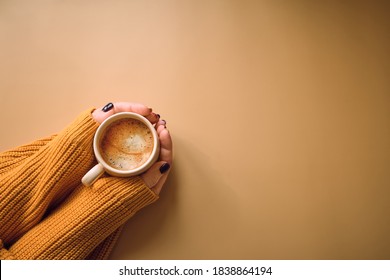 Autumn composition. Cup of coffee and with woman's hand, yellow sweater on pastel yellow background. Autumn, fall concept. Flat lay, top view, copy space