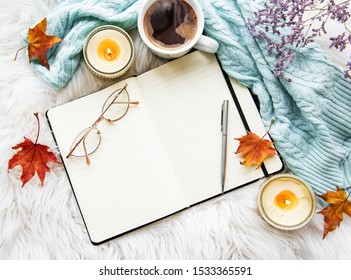Autumn composition. Cup of coffee, women fashion sweater, dried leaves,  notebook. Autumn, fall concept. Flat lay, top view, copy space
