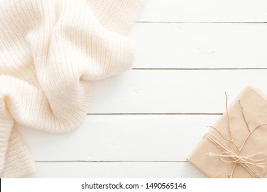 Autumn Composition. Feminine Desk Table With Knitted Scarf And Gift Box On Wooden White Background. Flat Lay, Top View. Nordic, Hygge, Cozy Home Concept