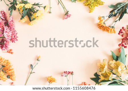 Autumn composition. Frame made of fresh flowers on pastel beige background. Autumn, fall concept. Flat lay, top view, copy space
