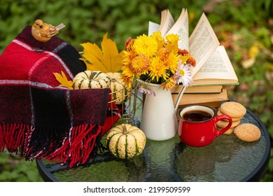Autumn composition in autumn garden. Warm woolen red blanket, pumpkin, coffee cup, cookies, books, decorations, autumn leaves on table. Fall background - Powered by Shutterstock