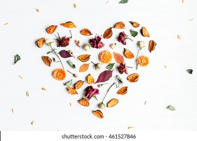 Autumn composition. Heart symbol made of dried flowers and autumn leaves. Top view, flat lay.