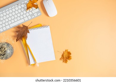 Autumn Composition. Office Desk With Empty Notebook, Keyboard, Dry Leaves On Isolated Beige Background. Autumn, Fall Business Concept. Flat Lay, Top View, Copy Space