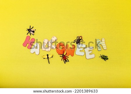 Autumn composition on a yellow background. The word Halloween and insects