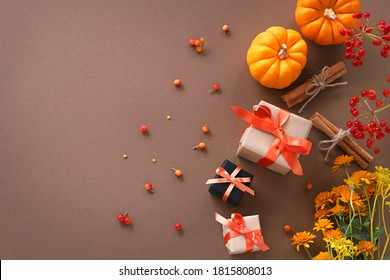 Autumn composition with orange pumpkin ,pine cones, cinnamon sticks, flowers and small gifts.
Flat lay, top view.