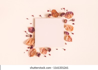 Autumn composition. Paper blank, dried flowers and leaves on pastel beige background. Autumn, fall concept. Flat lay, top view, copy space
