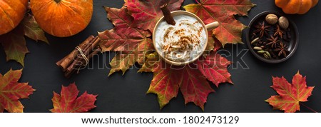 Autumn composition - Pumpkin Spice Latte,  maple leaves and pumpkin on black background, creative flat lay, top view, banner. Seasonal autumn concept with coffee drink.
