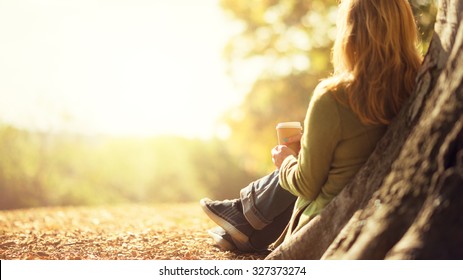 Autumn concept, anonymous woman enjoying takeaway coffee cup on sunny cold fall day