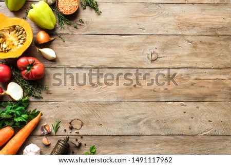 Autumn cooking background with seasonal organic vegetables on wooden table, top view, copy space. Ingredients for autum seasonal soups and dishes.