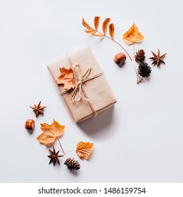 Autumn creative holiday present. Handmade paper gift box with foliage dried leaves, pine cones and nuts on white. Thanksgiving day, fall background. Copy space - Powered by Shutterstock