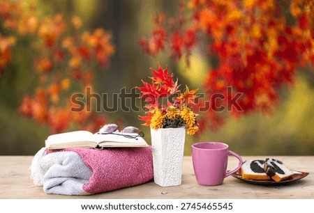 Autumn decor. Fall background. Soft autumn light creates a cozy and comforting scene outdoors. A cup of coffee and book under autumn fall leaves. Cozy autumnal feeling. Cozy autumn day for resting.