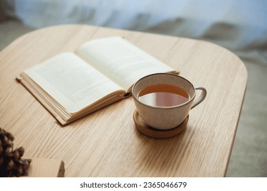 Autumn decor. Hot drink. Mug of tea, book on a wooden coffee table. Autumn. Fall. - Powered by Shutterstock