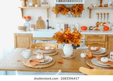 Autumn dining table setting with pumpkins and maple leaf bouquet. Natural wood surface.