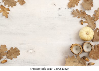 Autumn Dry Oak Leaves With Acorns, Mini Pumpkin And Candles On White Rustic Wood Background. Top View, Flat Lay.