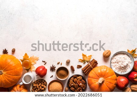 Autumn fall baking food background with pumpkins, apples, nuts and seasonal spices on white. Cooking pumpkin or apple pie and cookies for Thanksgiving and autumn holidays.