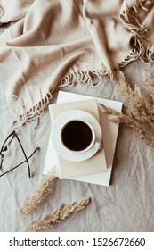 Autumn, Fall Composition. A Cup Of Coffee Lying On The Grey Linen Bed With Beige Warm Blanket, Books, Glasses And Reeds. Lifestyle, Hygge Concept. Flat Lay, Top View.