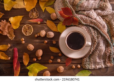 Autumn, fall leaves, hot cup of coffee and warm scarf on wooden table background, top view, copy space. Seasonal, morning coffee, sunday rest and still life concept.