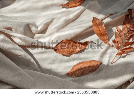 Autumn fall leaves and natural sunlight shadows on messy crumpled linen cloth background. Aesthetic autumn flat lay, business brand template.