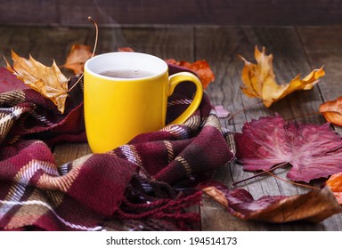 Autumn (fall) Still Life With Cup Of Tea, Warming Scarf And Colorful Leaves Over Rustic Wooden Background. Selective Focus, Shallow Dof