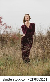 Autumn Fashion Outdoor Portrait Of Young Woman In Purple Red Plush Velvet Midi Dress. 