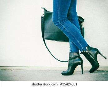 Autumn fashion outfit. Fashionable woman long legs in denim pants black stylish high heels shoes and handbag outdoor on city street - Powered by Shutterstock