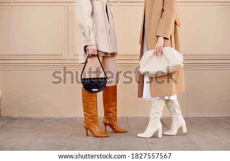 Autumn fashion two women in trendy clothes coat, high boots, bags . Street style outfit