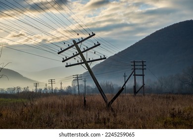 Autumn field with fallen electric poles at dawn. The wires were stretched dangerously under the weight of the support. Dramatic skies heighten the atmosphere of decadence - Shutterstock ID 2245259065