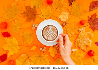 Autumn flat lay composition with dry leaves wreath frame and coffee latte cup in woman hand on bold orange color background. Creative autumn thanksgiving, fall, halloween concept. Top view, copy space - Powered by Shutterstock