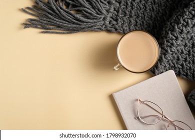 Autumn Flat Lay Composition. Top View Knitted Scarf, Coffee Cup, Glasses, Paper Notebook. Autumn Hygge Style Desk Table Or Winter Holiday Concept.