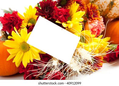 Autumn floral arrangement including daisies, carnations, mums, pumpkins, wheat and straw  on a white background with a blank notecard
