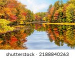 Autumn foliage reflections in calm pond water in New England
