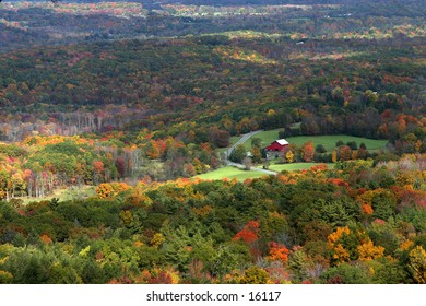 Autumn foliage in valley with red barn