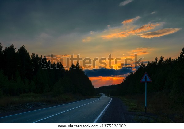 Autumn forest\
with country road at sunset. Colorful landscape with trees, rural\
road, sun in fall. Autumn\
background.