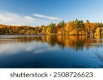 Autumn forest reflected on Moulin Lake (Lac du Moulin). Mont-Saint-Bruno National Park, Saint-Bruno-de-Montarville, Quebec, Canada. Fall foliage color.