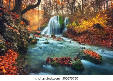 Autumn forest with waterfall at mountain river at sunset. Colorful landscape with trees, stones, waterfall and vibrant red and orange foliage. Nature background. Fall woods. Beautiful blurred water - Powered by Shutterstock