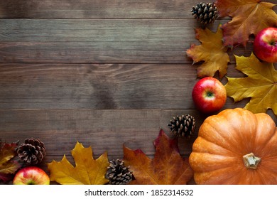 Autumn frame border with ripe orange pumpkin, red apples, pine cones and dry fallen leaves on dark wooden background. Happy Thanksgiving day concept. Flat lay, top view, copy space. - Powered by Shutterstock