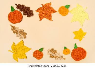 Autumn frame made of knitted toys in the shape of oak and maple leaves, orange pumpkins on a beige background with a place for text in the middle. Concept of autumn, Thanksgiving, Halloween - Powered by Shutterstock