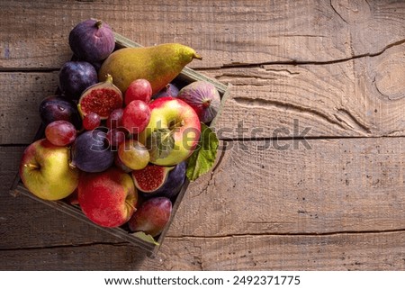 Autumn fruit assortment. Fall harvest seasonal fruits and berries - plum, apple, fig, pear, grapes, on a wooden table copy space