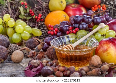 Autumn fruits, nuts and vegetables with honey on the table